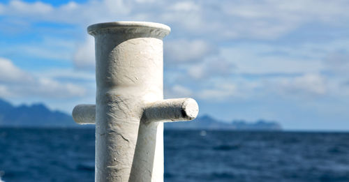 Close-up of wooden post in sea against sky