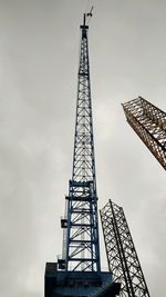 Low angle view of crane against cloudy sky