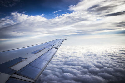 Aerial view of airplane wing against cloudy sky