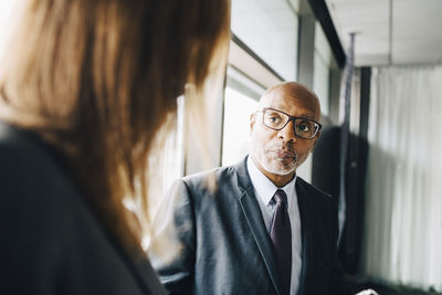 Senior executive looking at female coworker while standing in board room at office