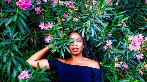 Portrait of young woman standing by flowering plants