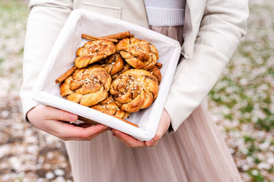 Girl with a basket of cinnamon rolls in her hands.