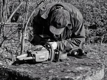 Man repairing chainsaw on field