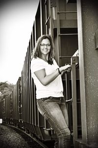 Portrait of smiling young woman standing against built structure