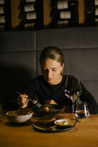 Young woman eating meal at dining table in restaurant