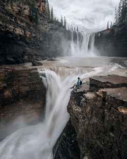 High angle view of man sitting by waterfall