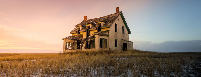 Abandoned house on field against sky during sunset