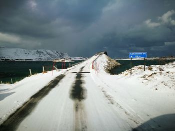 Road leading towards snow covered mountain against sky