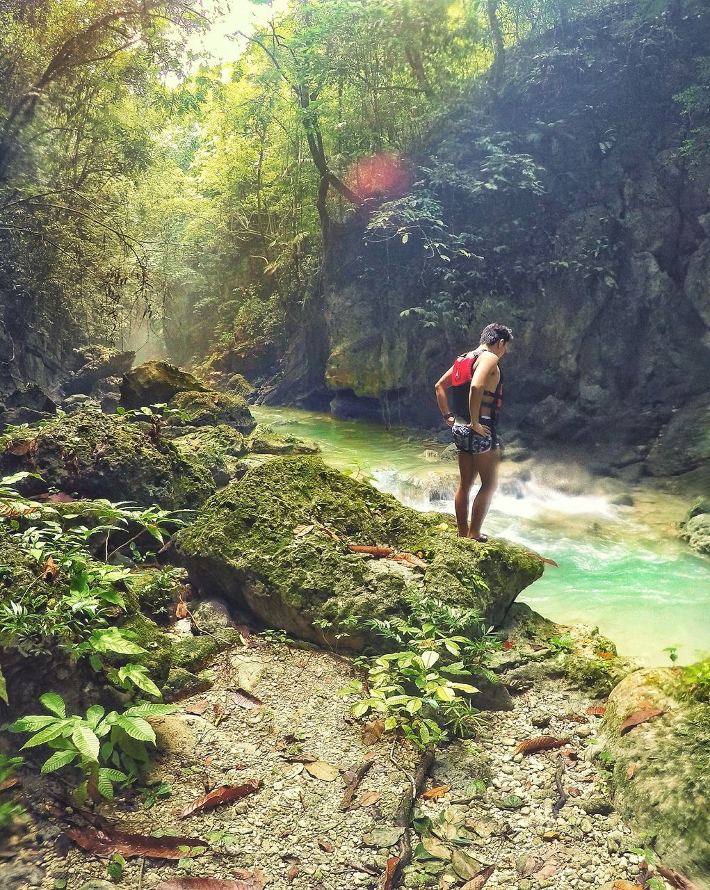 WOMAN STANDING ON ROCK IN FOREST