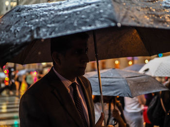 Portrait of man holding umbrella during rainy season
