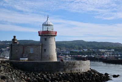 Lighthouse by building against sky