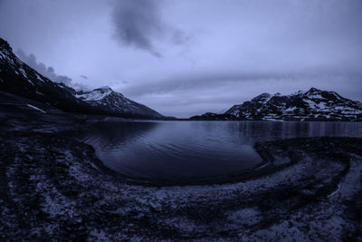 Scenic view of lake by snowcapped mountains against sky