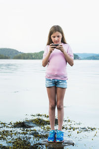 Girl with cell phone at water