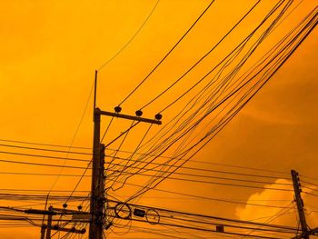 Low angle view of silhouette electricity pylon against sky during sunset