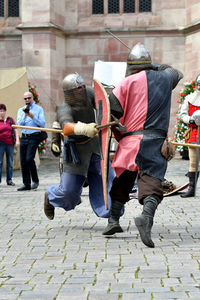 People looking at men in period costume fighting during knight tournament