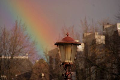 Close-up of lamp post against rainbow in sky