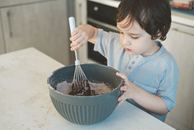 A little boy is cooking in the kitchen.