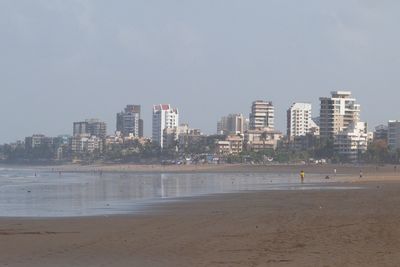 City buildings by sea against sky