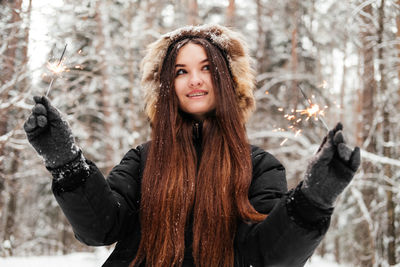 Portrait of young woman standing against trees