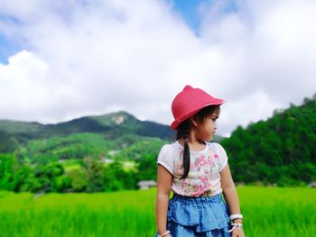 Cute girl standing on field against sky