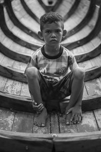 Portrait of boy sitting on built structure