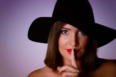 Portrait of young woman wearing hat against gray background