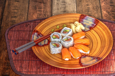 Salmon sushi rolls and sake with wasabi, ginger and chopsticks