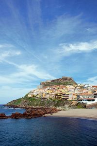 Buildings by sea against sky in town