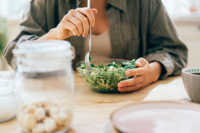 Cropped unrecognizable woman eats healthy green vegetable salad.