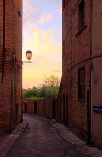 Street amidst buildings against sky during sunset