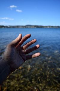 Close-up of hand against sea 