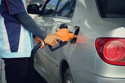 Midsection of man refueling car 