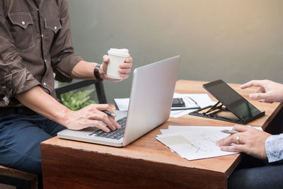 Midsection of woman using laptop while sitting on table