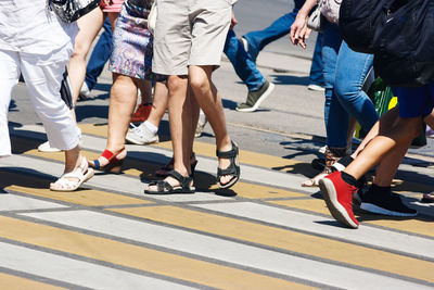 Low section of people walking on zebra crossing in city