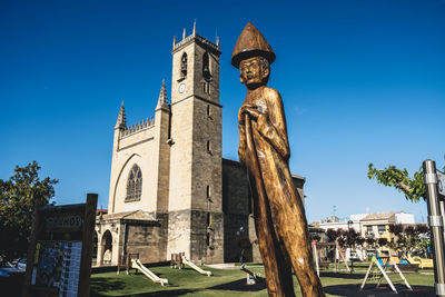 Low angle view of statue against building against clear blue sky