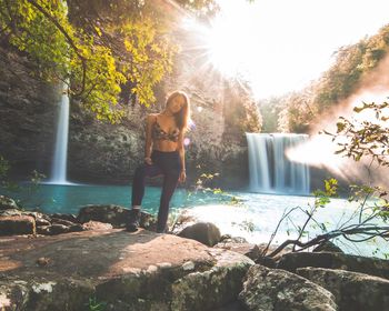 Portrait of young woman standing mountain by waterfall