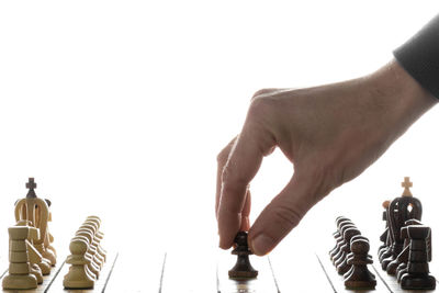 Low angle view of man holding chess against white background