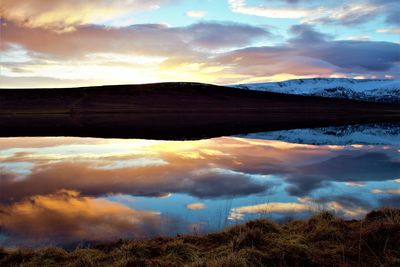 Scenic view of dramatic sky over land during sunset