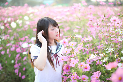 Beautiful woman standing by pink flowering plants