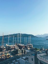 Boats moored in harbor against clear sky