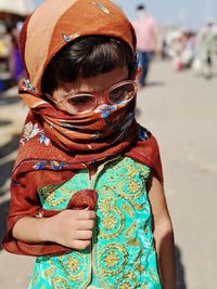 Girl with covered face standing on footpath