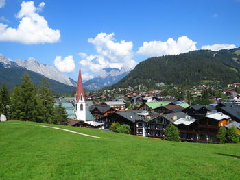 Scenic view of field by buildings against sky