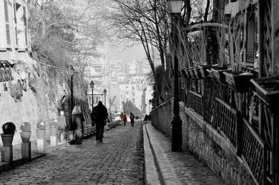 Rear view of people walking on street amidst buildings