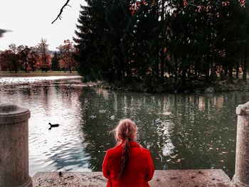 Rear view of woman standing by lake