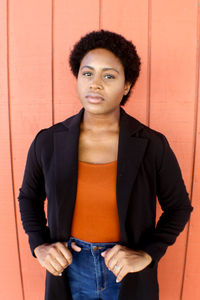 Portrait of a young woman standing against wall