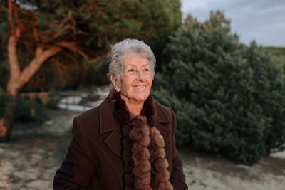 Portrait of smiling woman standing against trees during winter