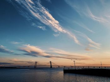 Silhouette bridge over sea against sky during sunset