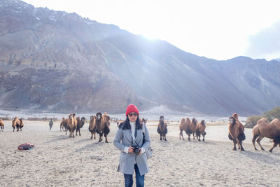 Woman standing in desert against animals and mountains