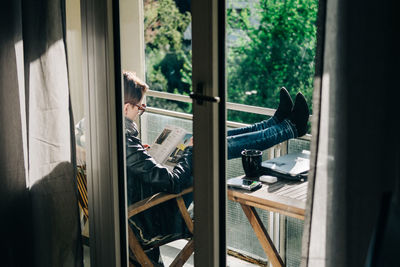 Young woman reading a magazine in the balcony