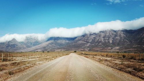 Road leading towards mountains against sky